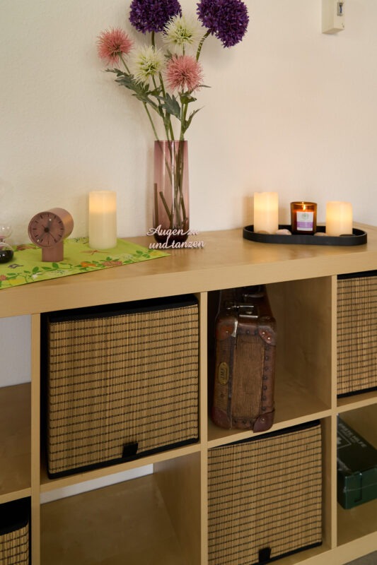 Nahaufnahme eines Regals mit einer dekorativen Blumenvase, einigen Kerzen und meinem Zauberkoffer.