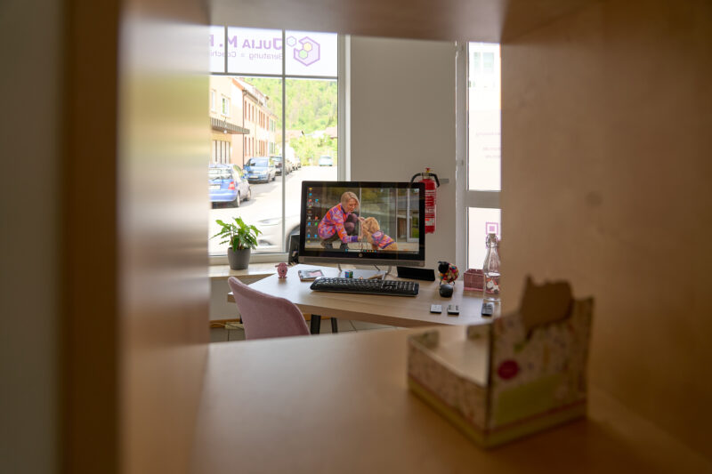 Ein Blick durch ein Regal hindurch auf den PC an meinem Arbeitsplatz mit einem Blick auf die Straße durch das Schaufenster.