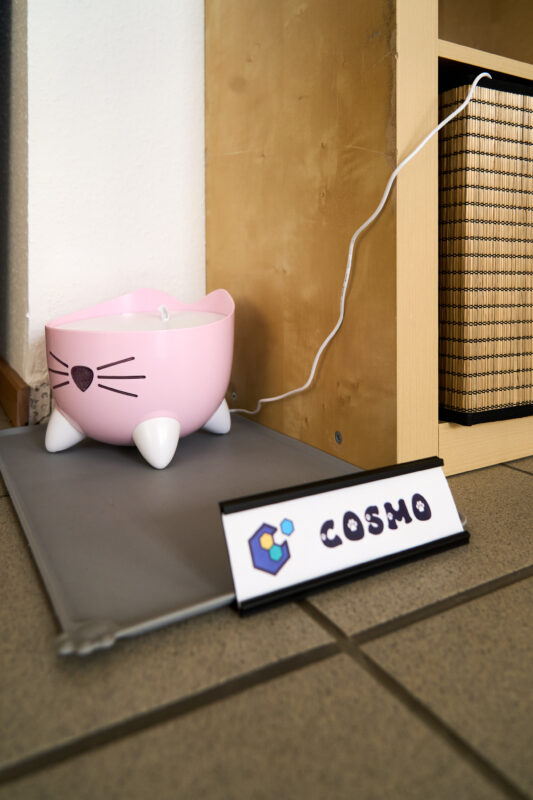 Eine Nahaufnahme, die Cosmos Trinkbrunnen und sein Namensschild zeigt.