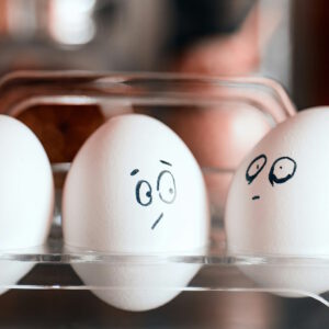 Symbolbild für Eifersucht - drei Eier, die jeweils mit unterschiedlichen Gesichtsausdrücken bemalt sind.