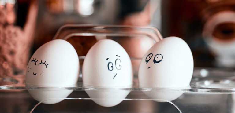 Symbolbild für Eifersucht - drei Eier, die jeweils mit unterschiedlichen Gesichtsausdrücken bemalt sind.
